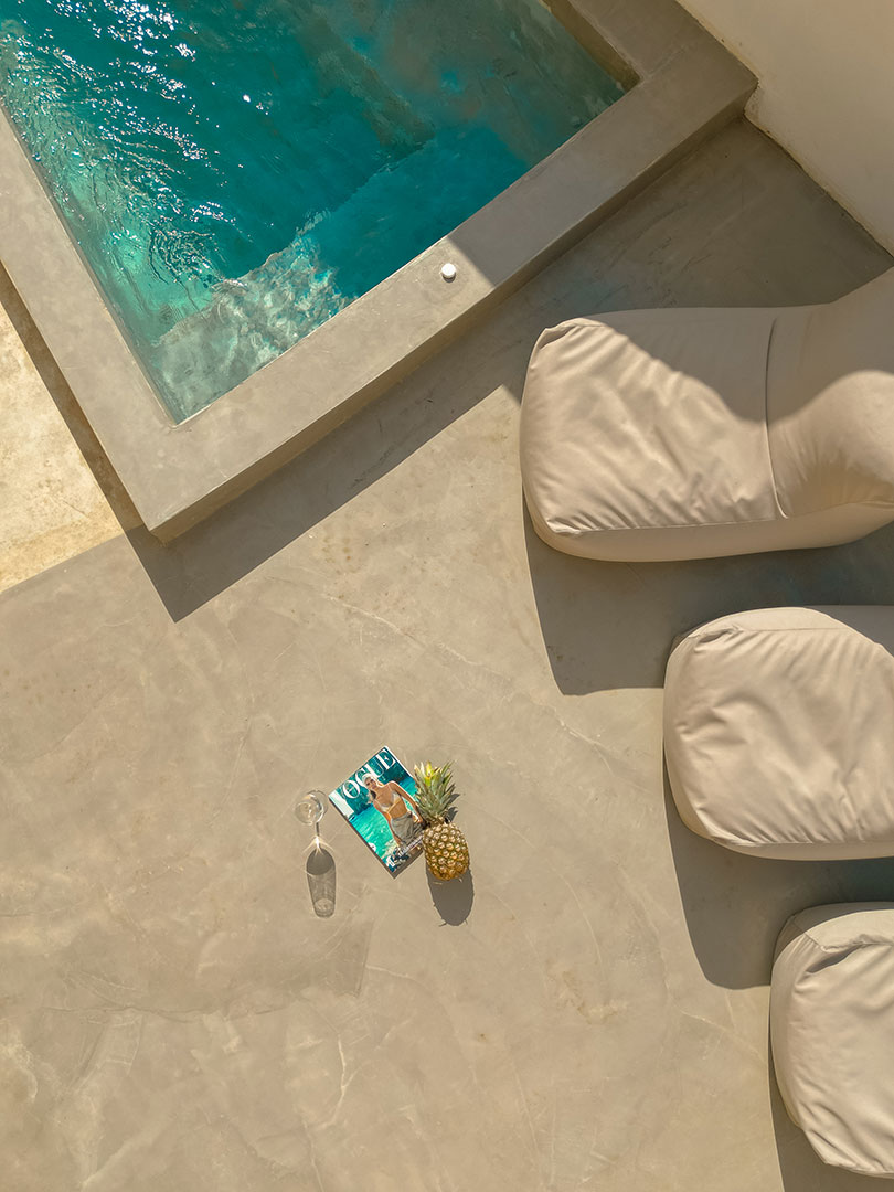 Nami Hotel Suites pool, sunbeds and a drink, a pineapple and a magazine in the middle