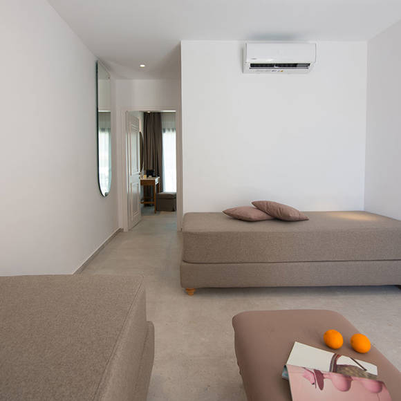 Nami Hotel Suites Suite living room with two big couches, a smaller one as a table and bedroom view